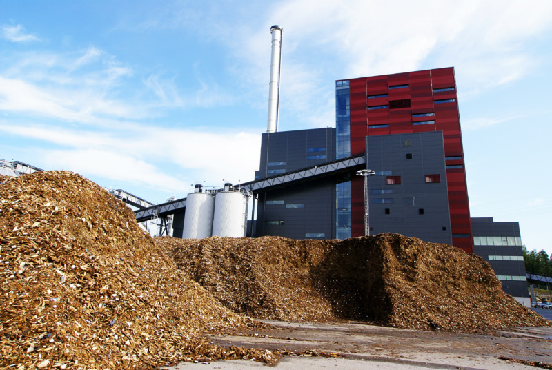 Bio power plant with storage of wooden fuel (biomass) against blue sky.