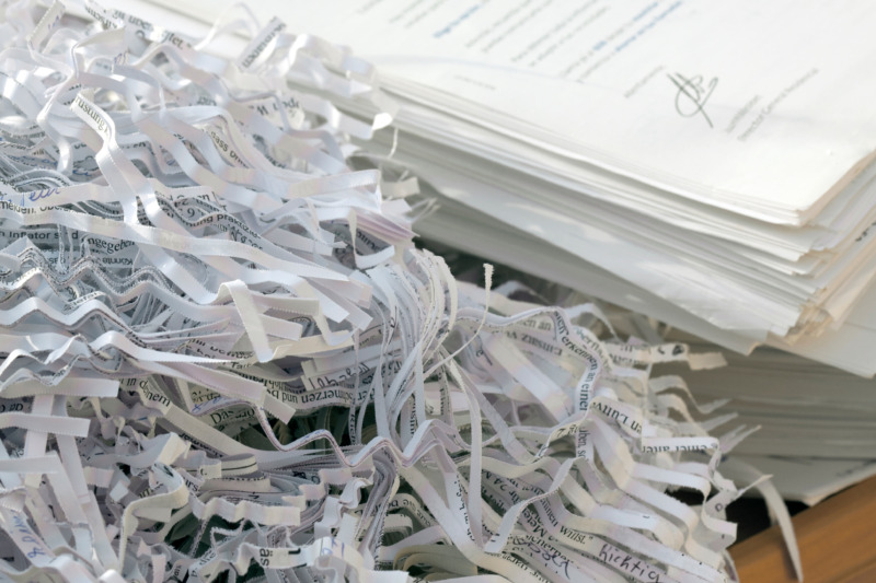A pile of confidential documents sit next to a pile of shredded paper.