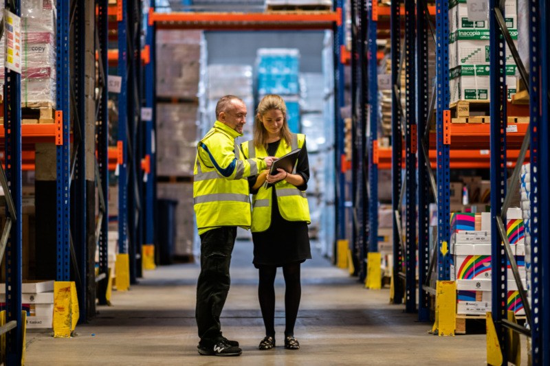 Two members of the Springfield Papers team talk in the warehouse.