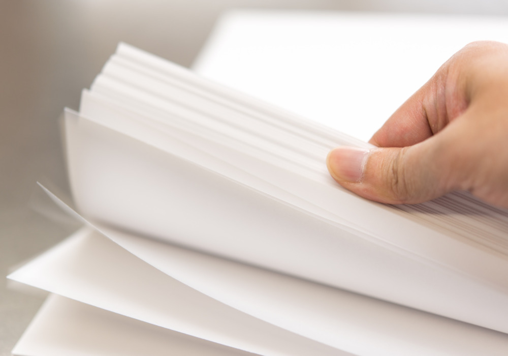 Paper stack with female hand flicking through it