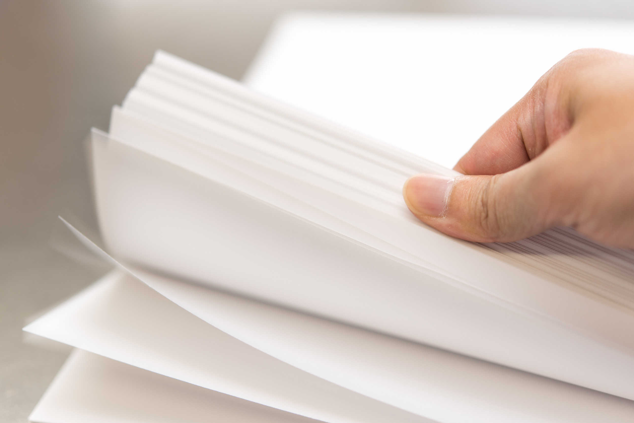 Paper stack with female hand flicking through it